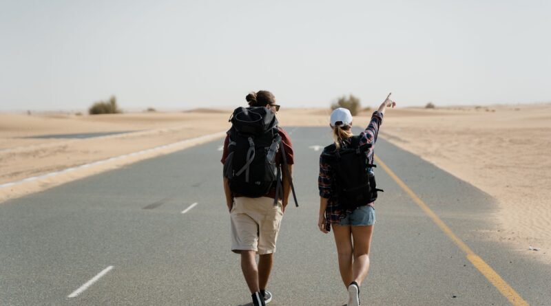 Casal a caminhar no deserto com mochilas grandes ás costas