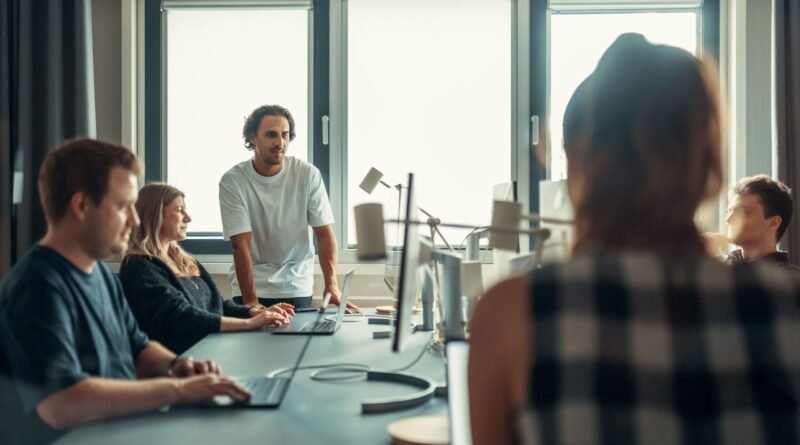 Grupo de pessoas sentadas á mesa de trabalho com computadores